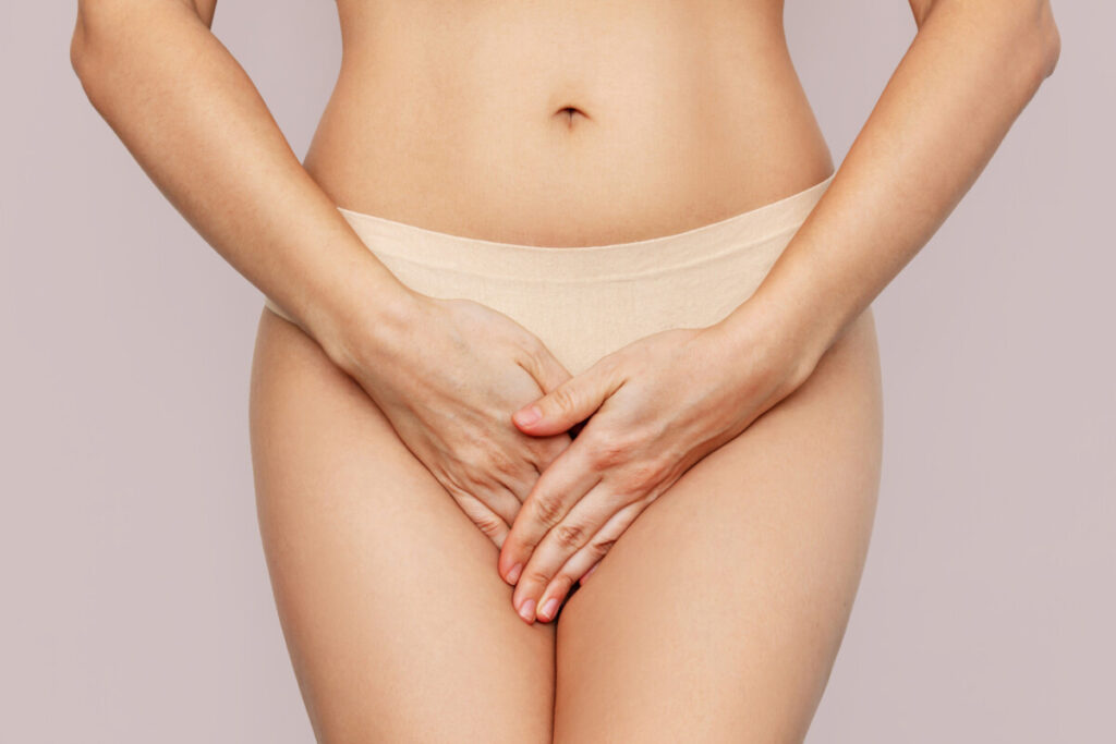 Young woman gently covering her pelvic area, suggesting intimate discomfort and seeking medical care. Optional Caption: "Private, empowering solutions for personal concerns—learn how labiaplasty can restore your confidence."