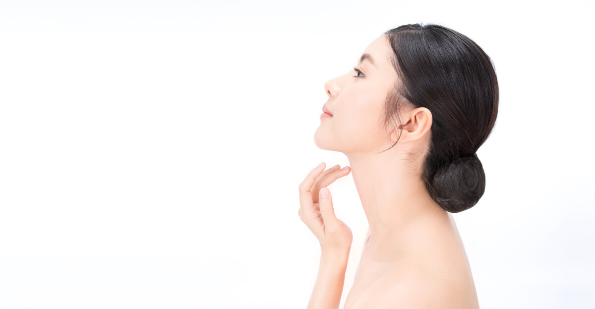 Close-up portrait of an Asian woman with flawless skin, gently touching her jawline, suggesting a sculpted, glowing profile.