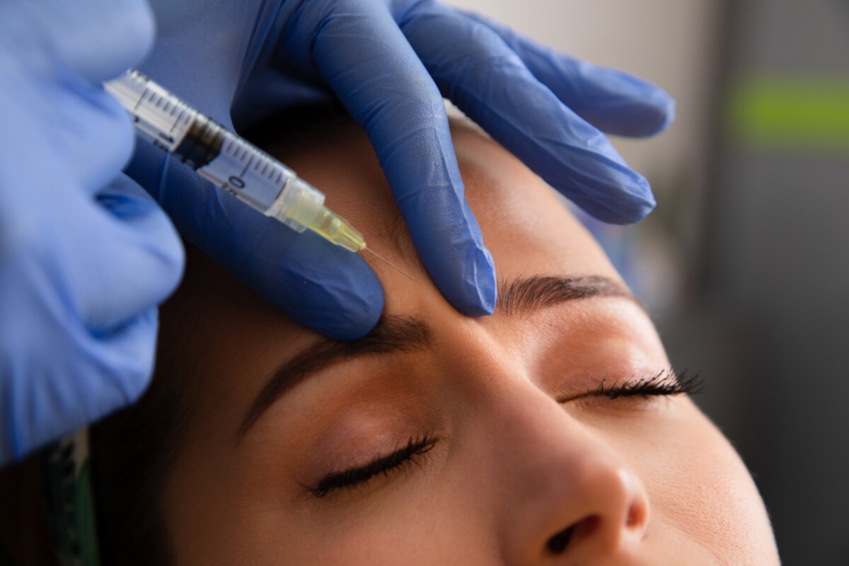 Close-up of a woman receiving a cosmetic injection near the forehead to smooth wrinkles.